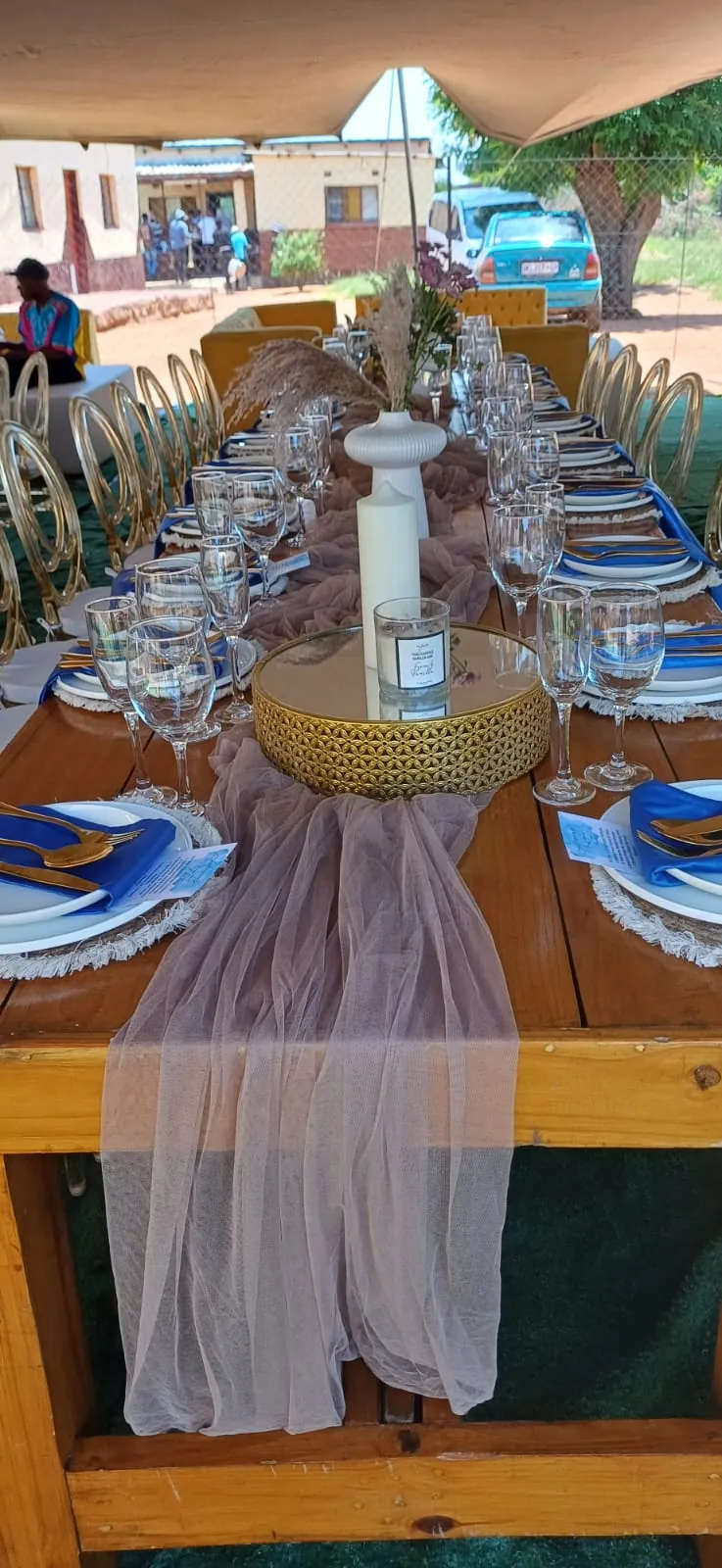 Long banquet table dressed with white linen, blue plates and glassware