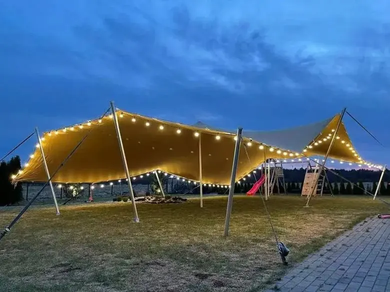 Stretch tent illuminated with string lights at dusk