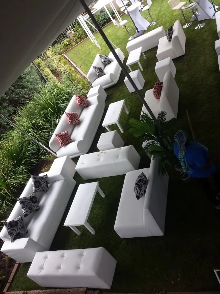 White lounge couches and coffee tables arranged on a garden lawn