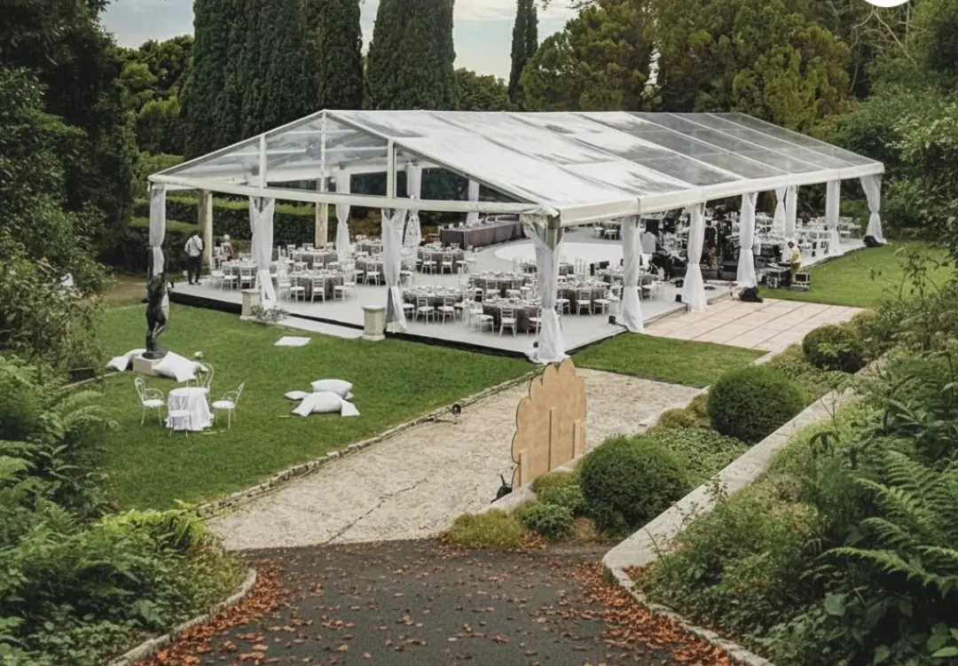 Clear-roof marquee with white chairs on a garden lawn