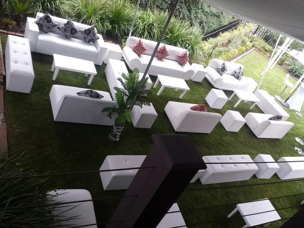 Aerial view of white leather lounge suites, ottomans and coffee tables arranged on a lawn for a garden event — premium VIP lounge furniture hire by Decorvent Hire Gauteng