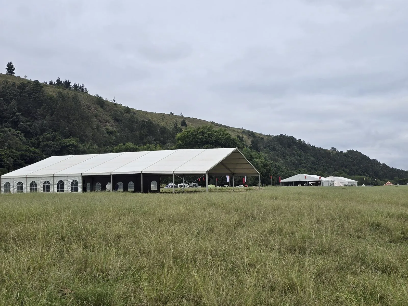 Large marquee tent in green field with mountain backdrop — corporate event Gauteng