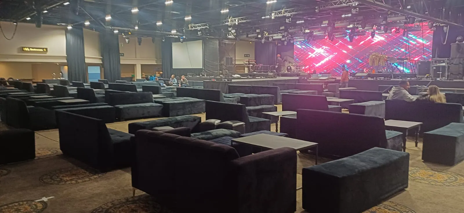 Dark velvet lounge couches at large corporate concert venue with LED stage — lounge hire Johannesburg Gauteng