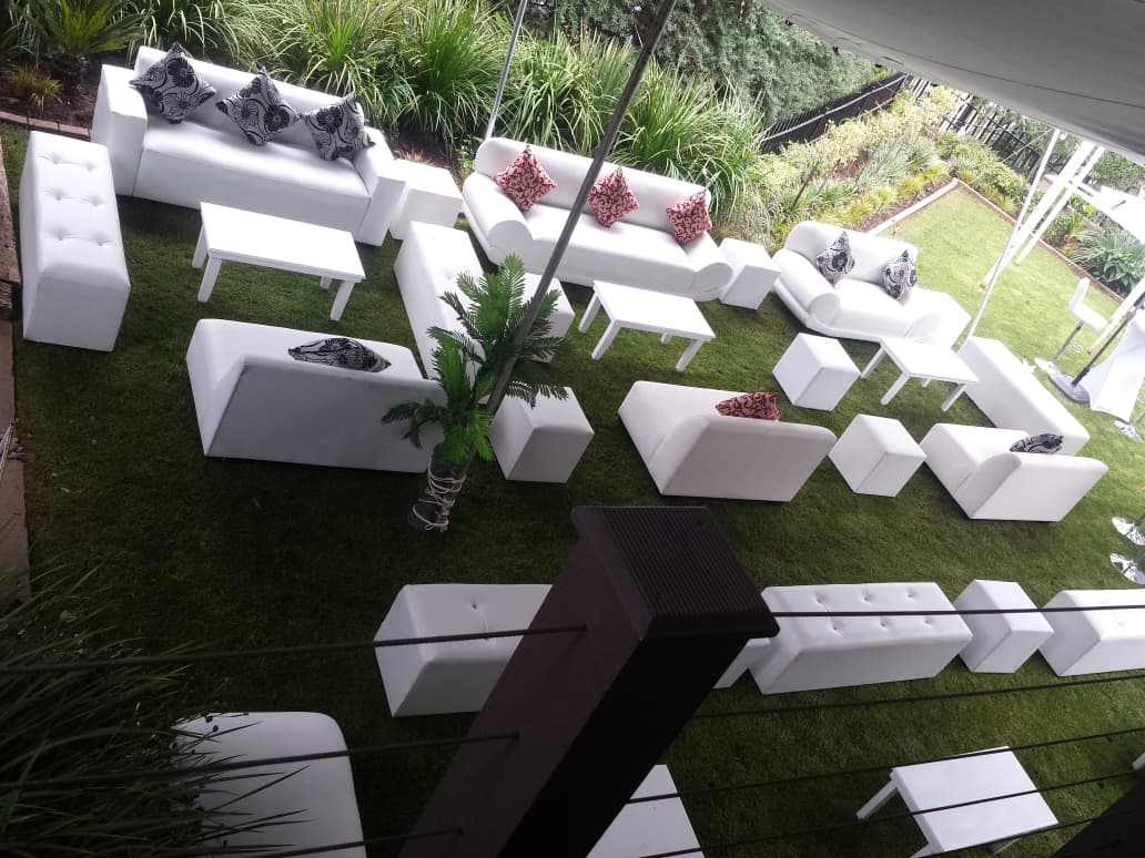 Aerial view of white leather lounge suites, ottomans and coffee tables arranged on a lawn for a garden event — premium VIP lounge furniture hire by Decorvent Hire Gauteng